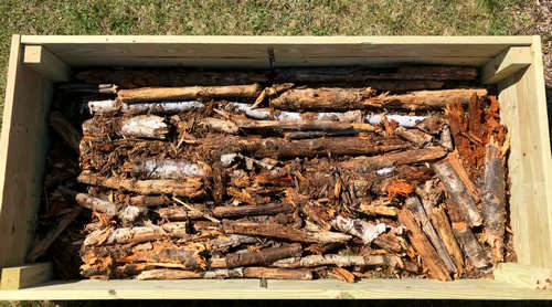 Raised bed partially filled with logs,